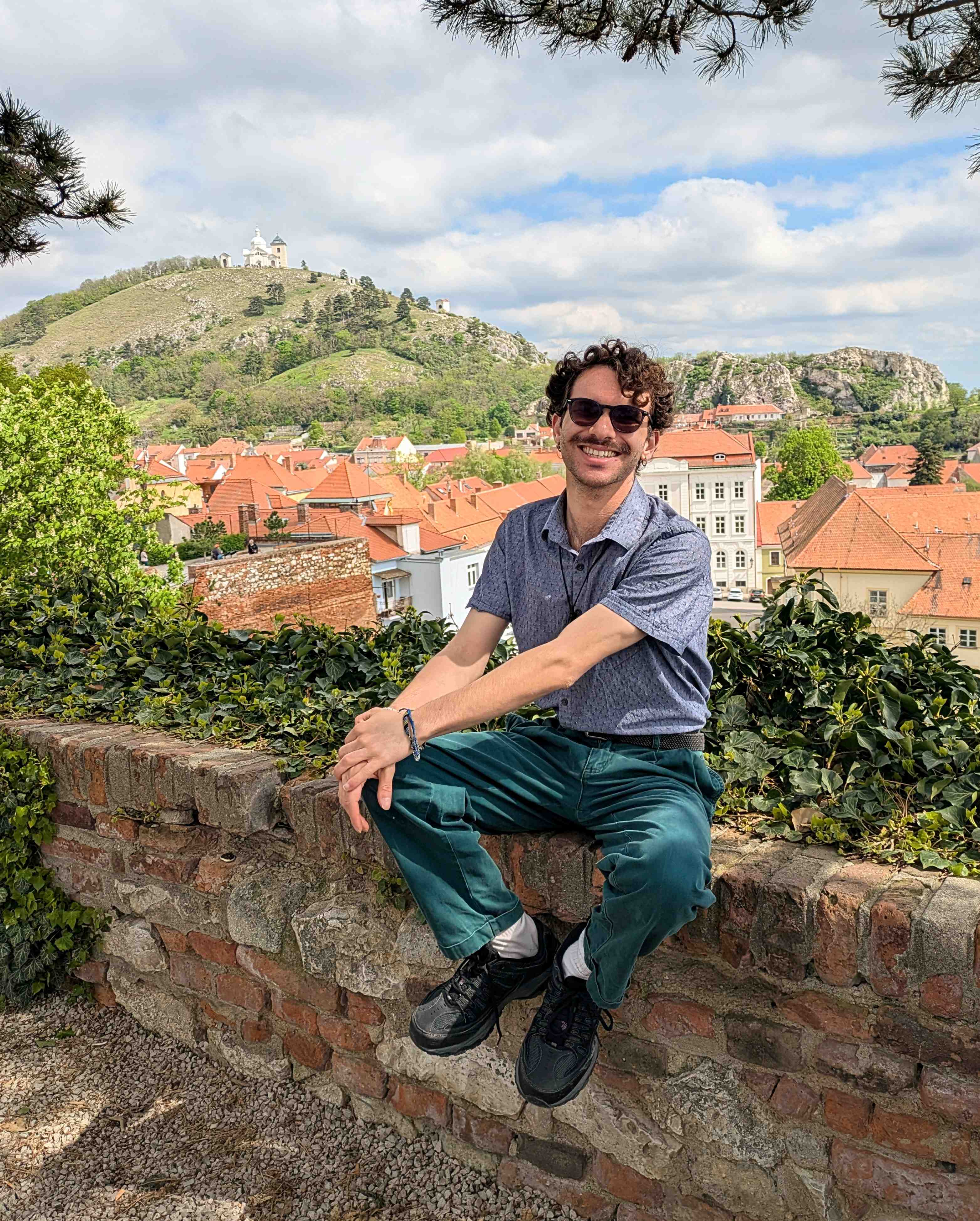 Picture of Daniel sitting on a ledge with a Czech town in the background on his 25th birthday