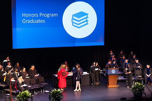 An honor student receives their diploma at graduation