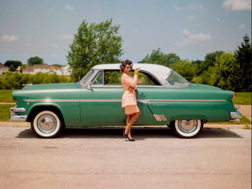 woman standing in front of a vintage car