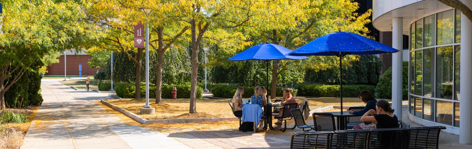 Harper College employees eat lunch at outdoor tables outside of Building W