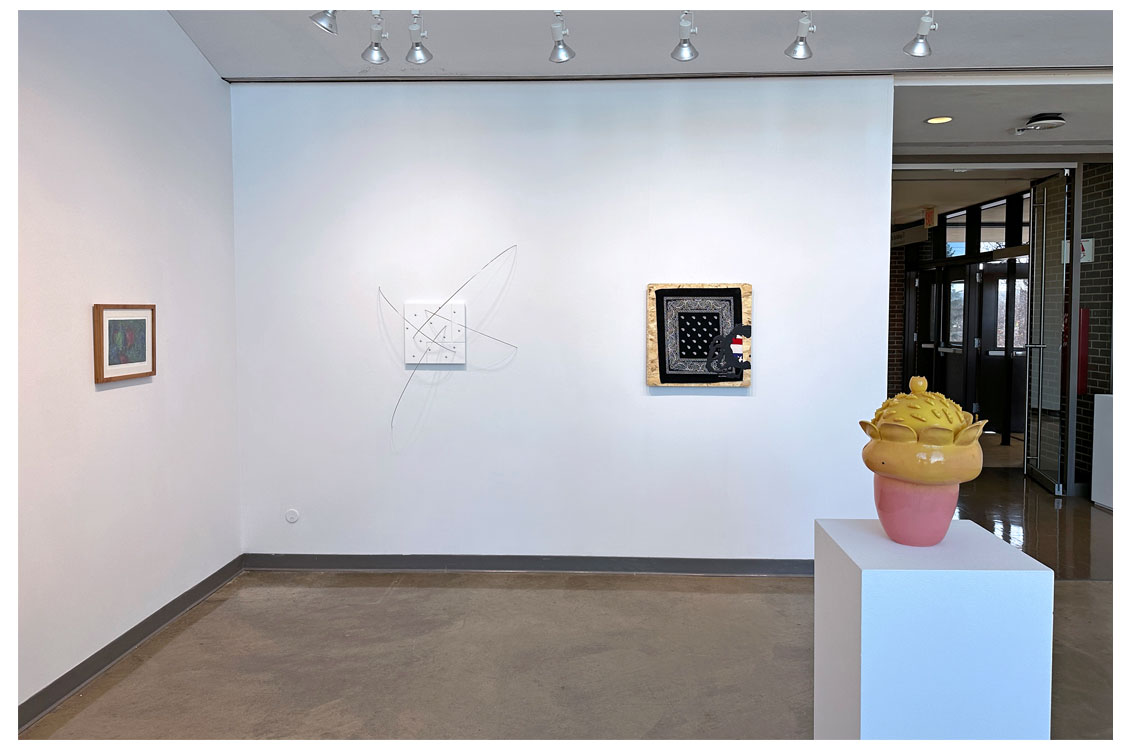 interior gallery view of paintings on wall and sculpture in the foreground