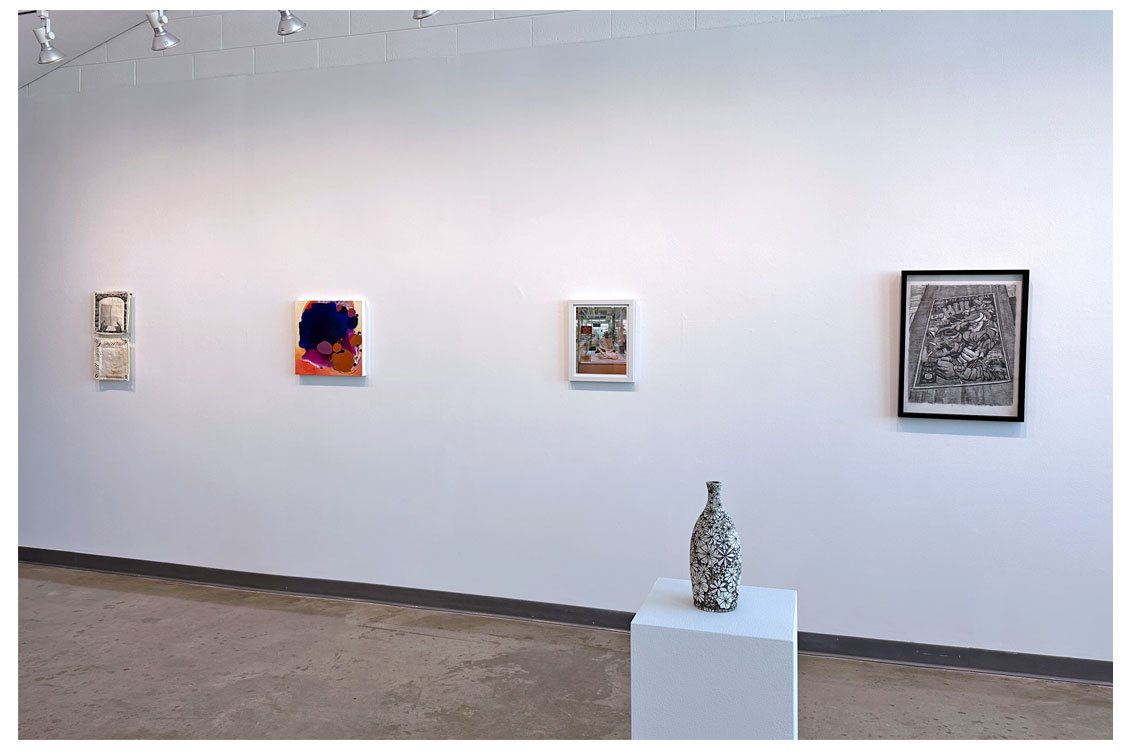 interior gallery view with paintings on wall and vase on display in foreground