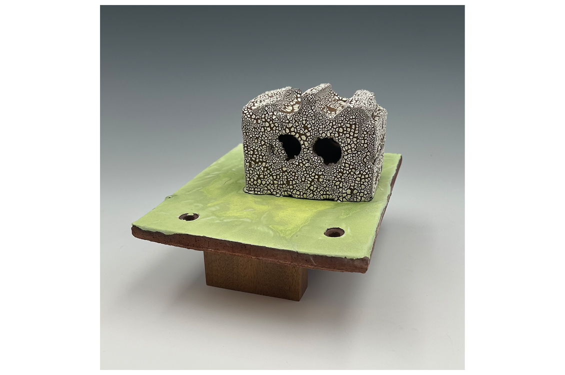 abstract sculpture of a metallic block on a green wood board