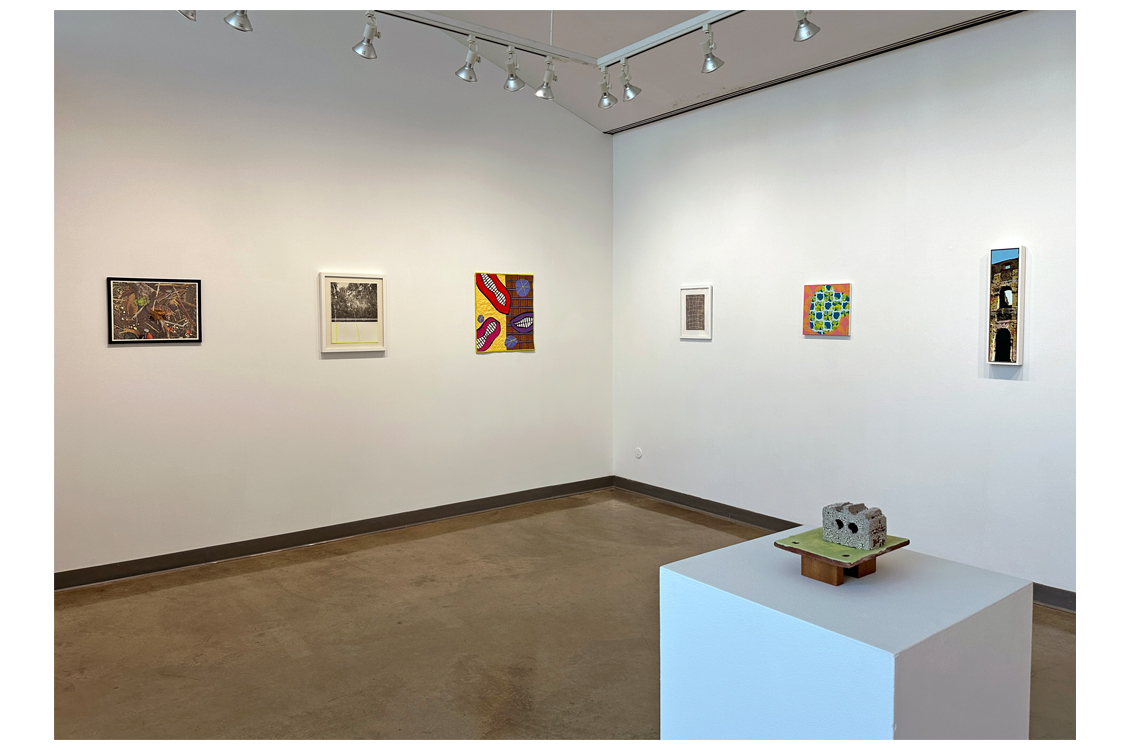 Corner of gallery with paintings on wall and sculpture on display