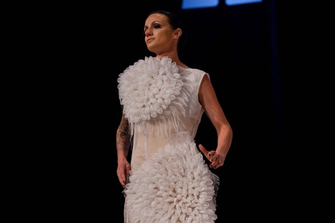 Model in a sheer white dress with sections puffed in a texture like flower petals