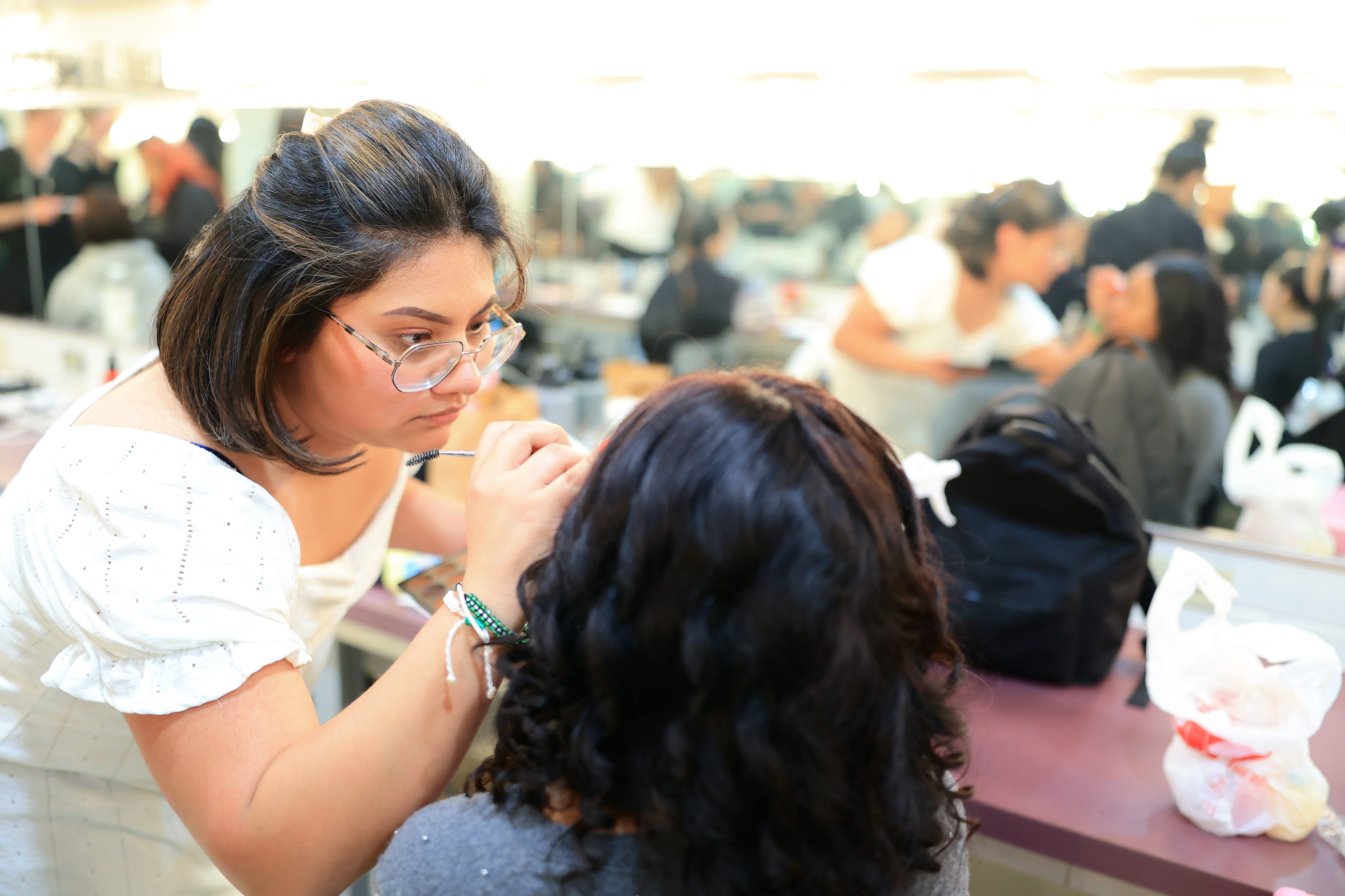 A makeup artist putting makeup one one of the models back stage