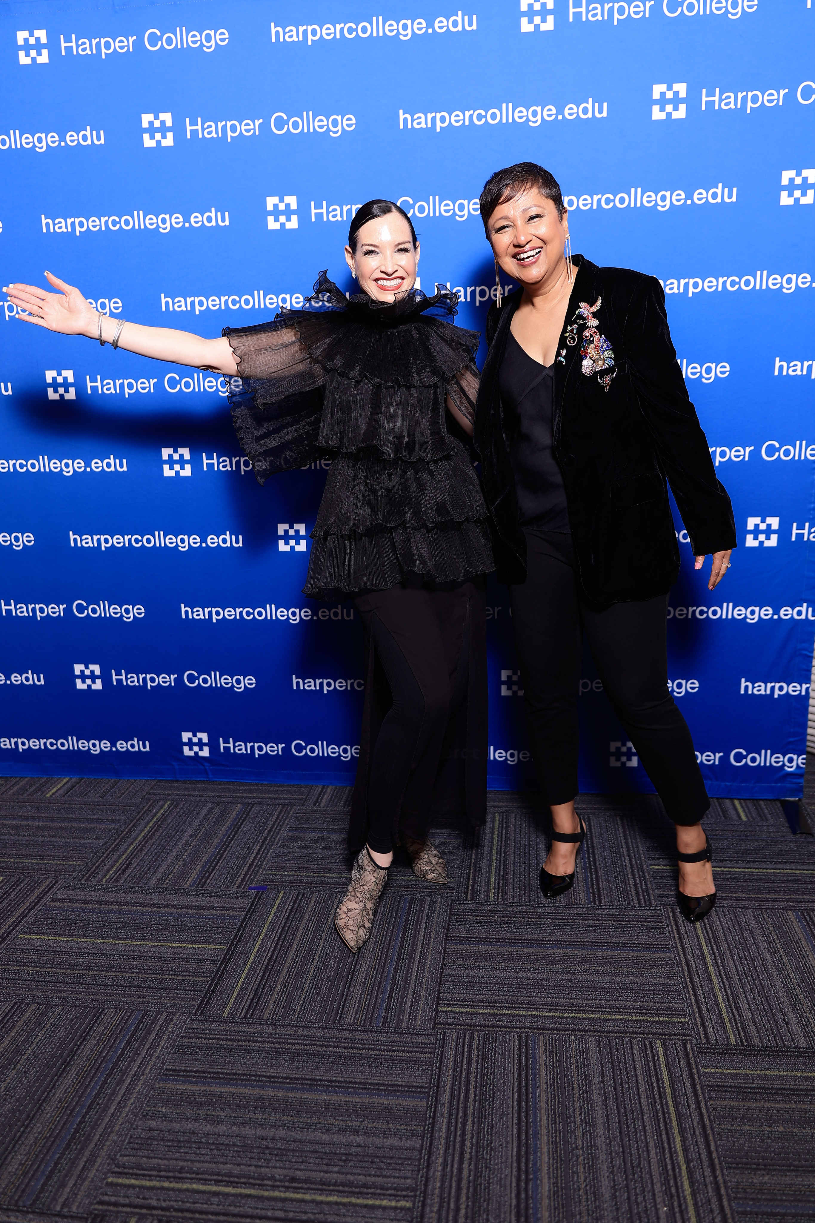 Two women posing in front of Harper College background