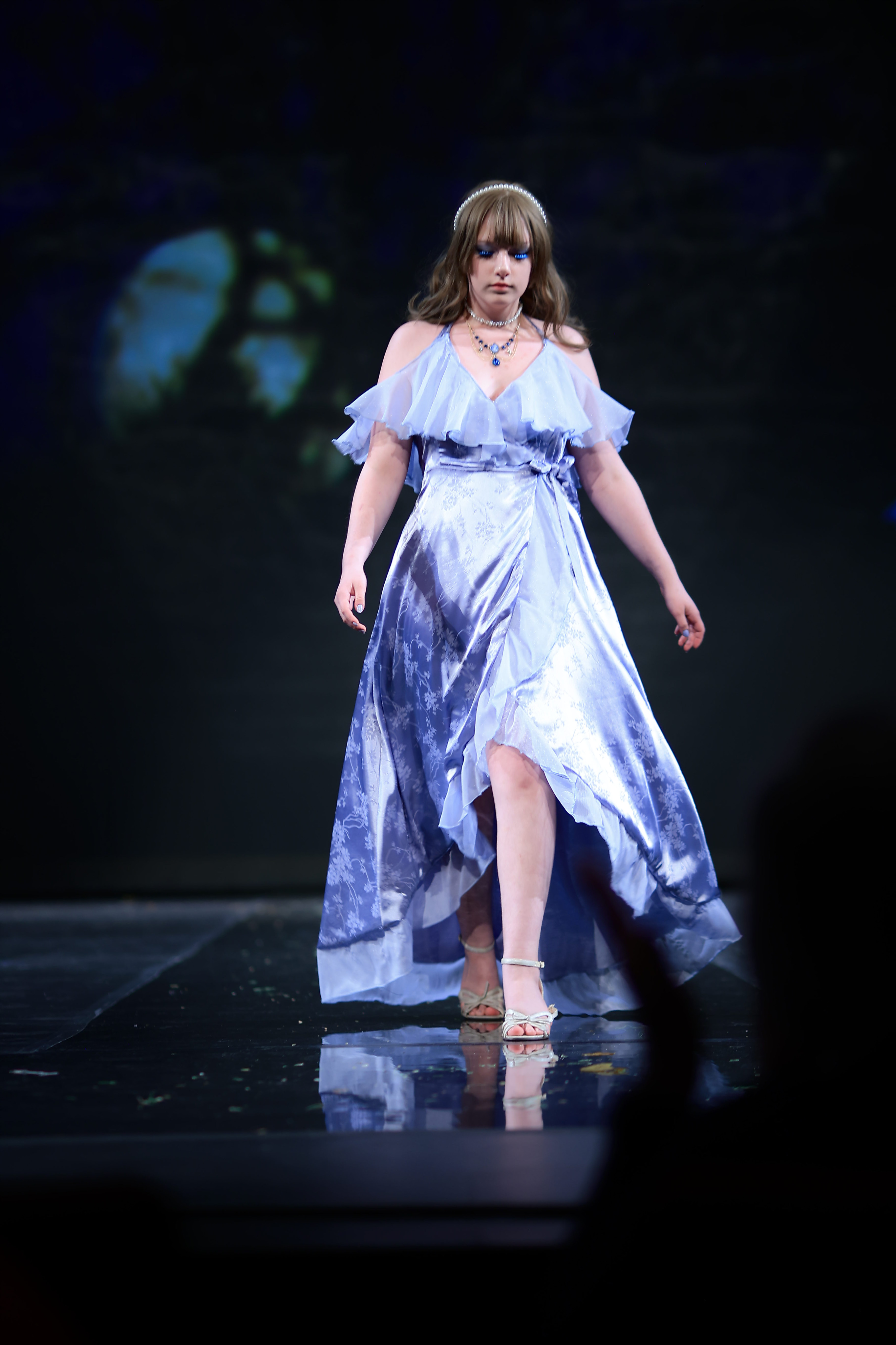 Model wearing a lavender colored dress with floral pattern and silver heels.