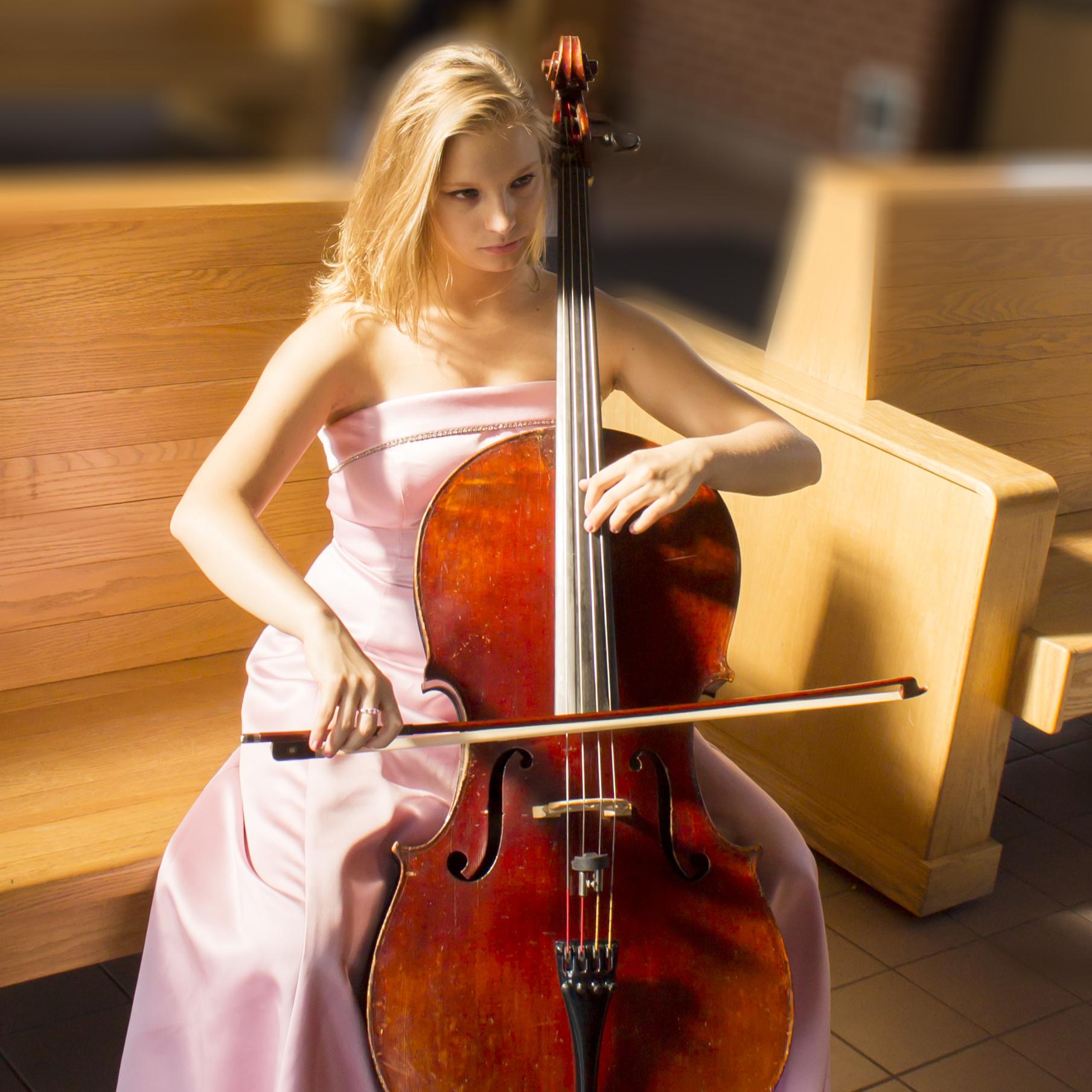 Jessica Bieniarz playing the cello in a pink dress.