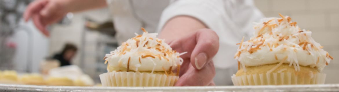 A chef places cupcakes down in a row.