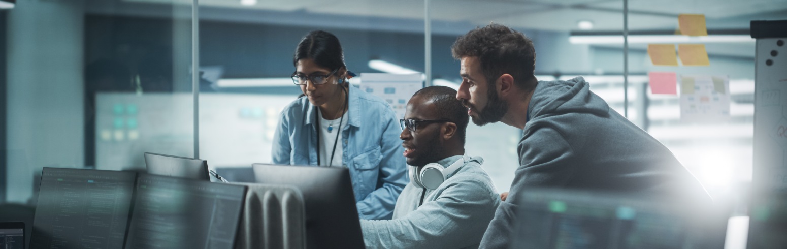 A man works on a computer and collaborates with his colleagues in an office