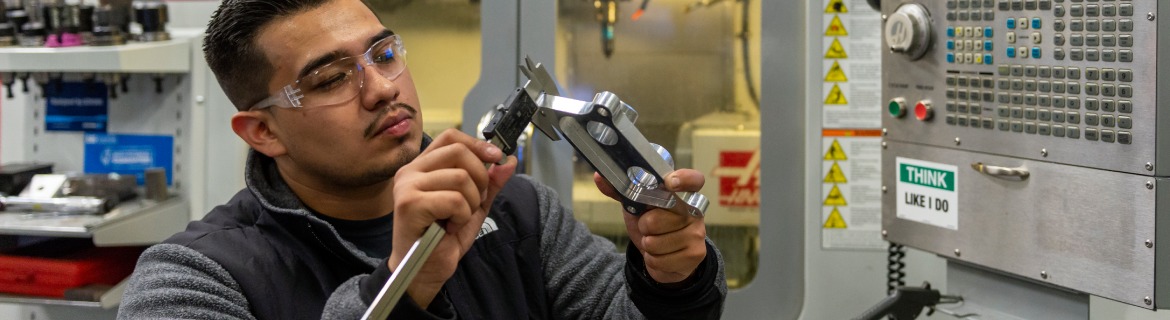 Harper College Engineering program student working with industrial machinery.