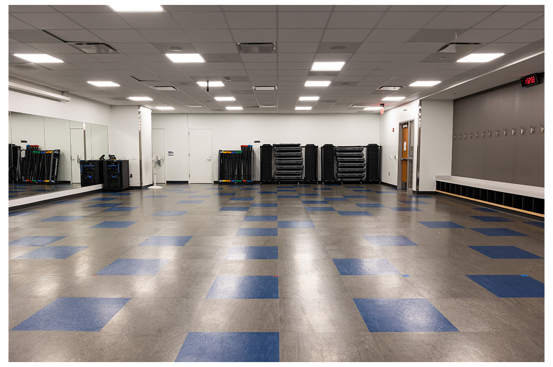 An empty gym room with equipment along the wall 