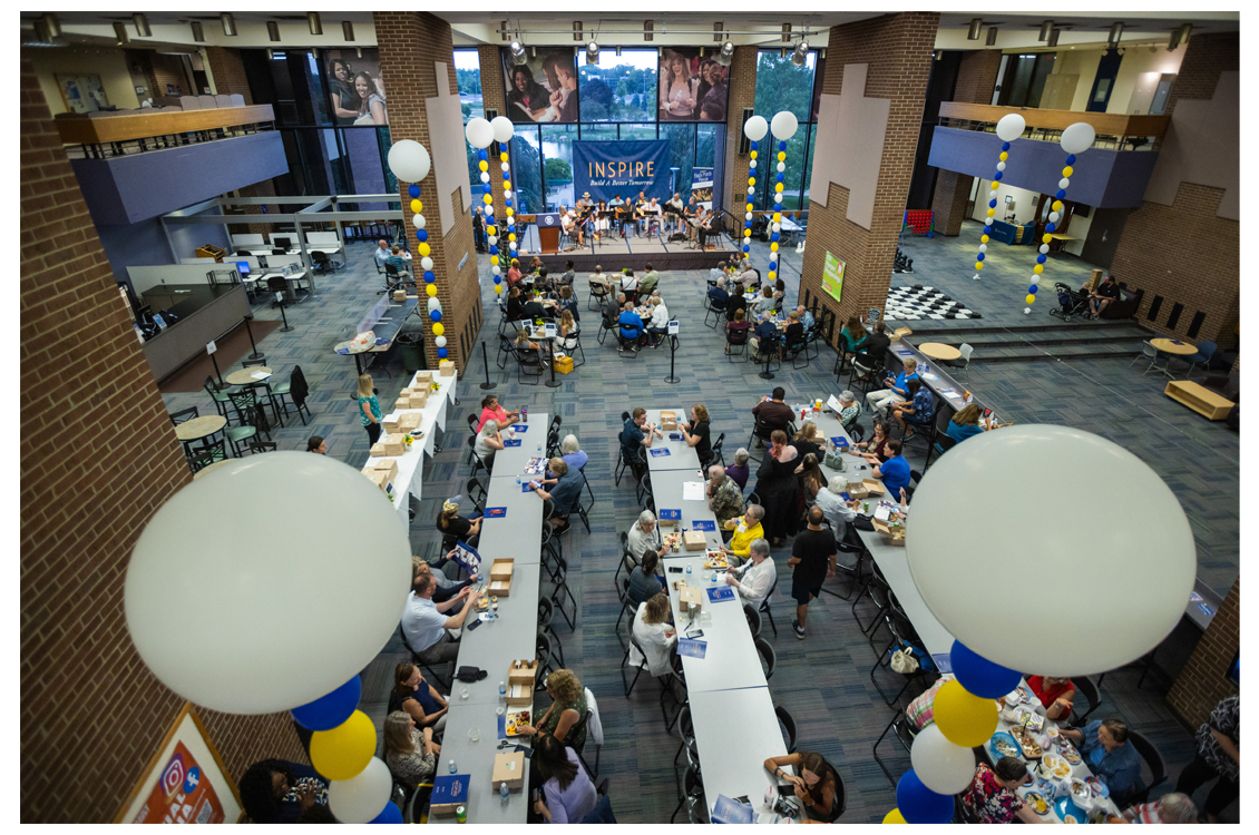 people gathered at long tables in a large open study space