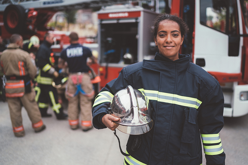 Firefighter in gear standing in front of a fire truck