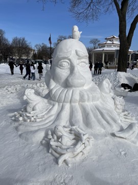 A snow sculpture of a male head surrounded by bird nests.