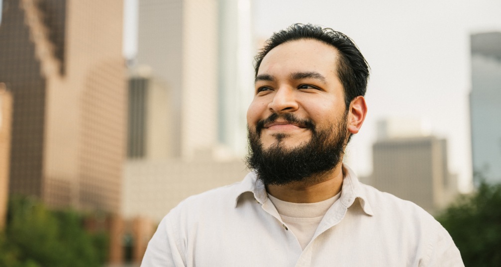 man walking through city and smiling with a hopeful expression