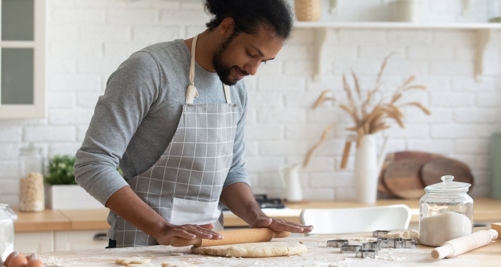 a man rolling out dough to bake in his home kitchen