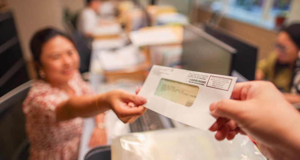 a woman handing away an envelope containing a refund to a person's waiting hand