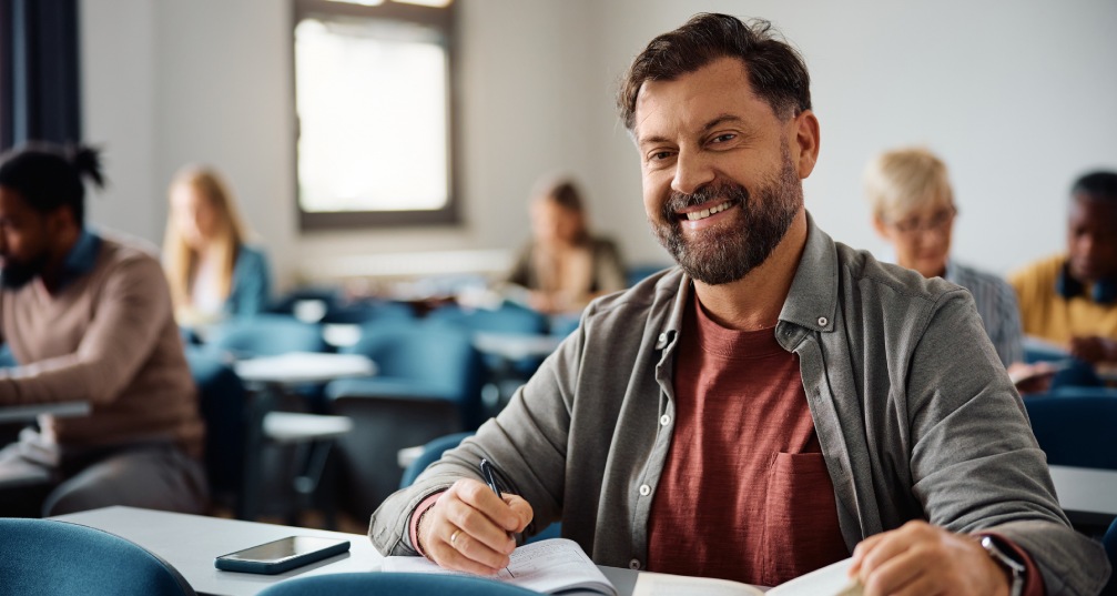 a smiling middle aged man sits in class