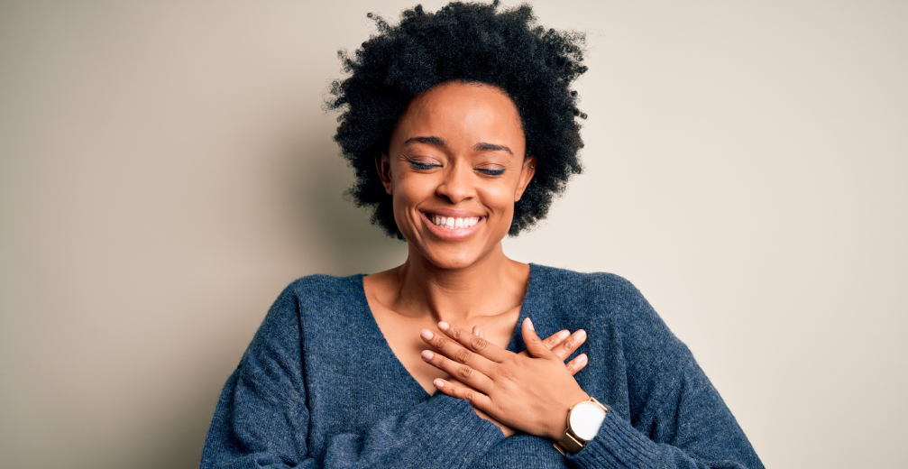 Smiling woman with hands over her heart.