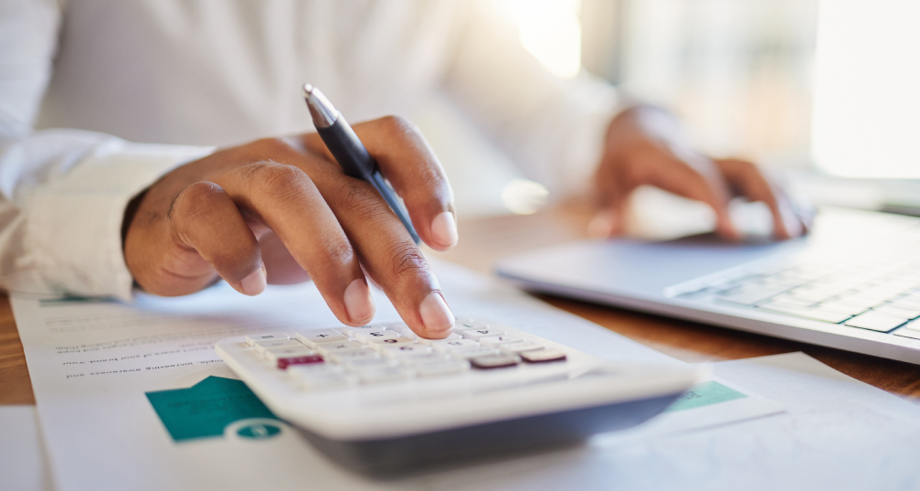 a view of a man's hands working on a budget using a computer and calculator