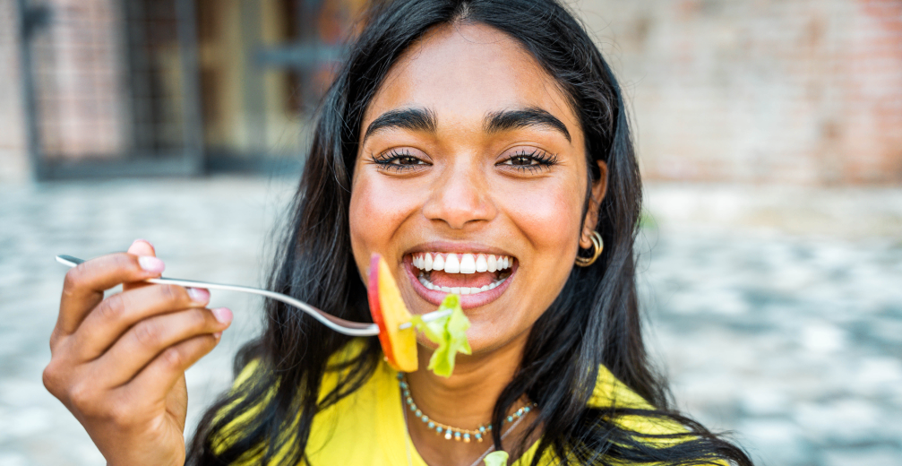 Smiling woman holding a fork and salad bowl.