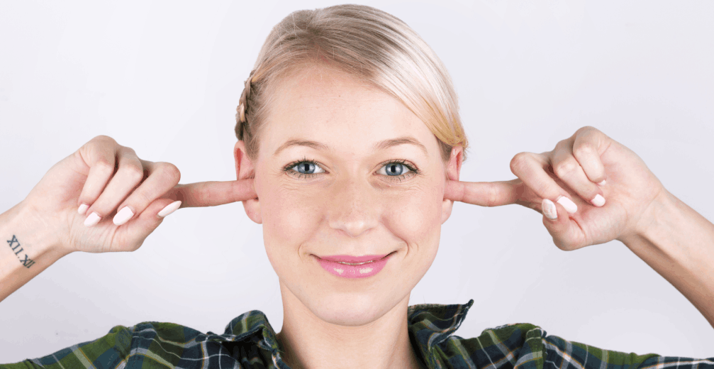 Smiling woman plugging her ears with her fingers.