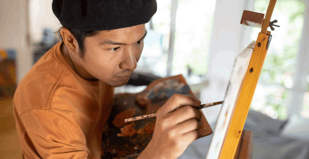 Artist focused on painting at an easel.