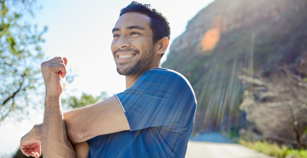 Man stretching outdoors with a smile.