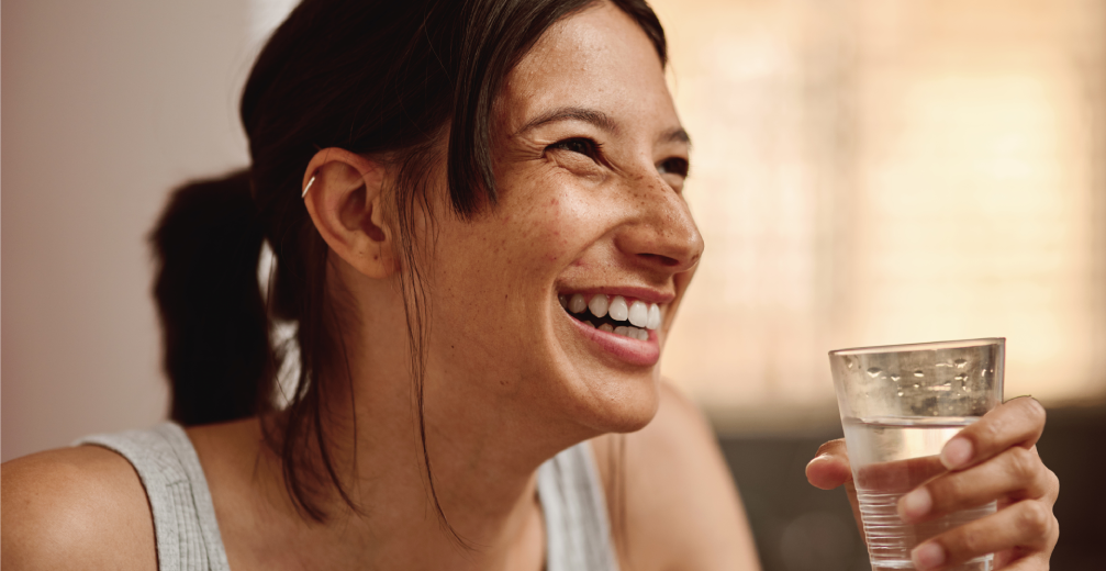 Smiling woman holding a glass of water.