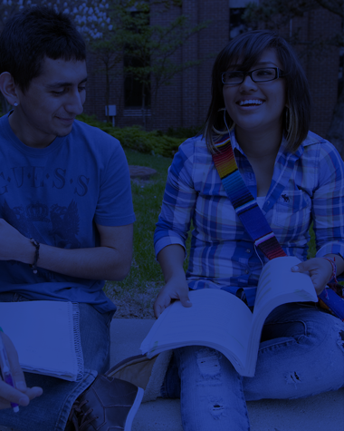 two students with open books sitting and talking