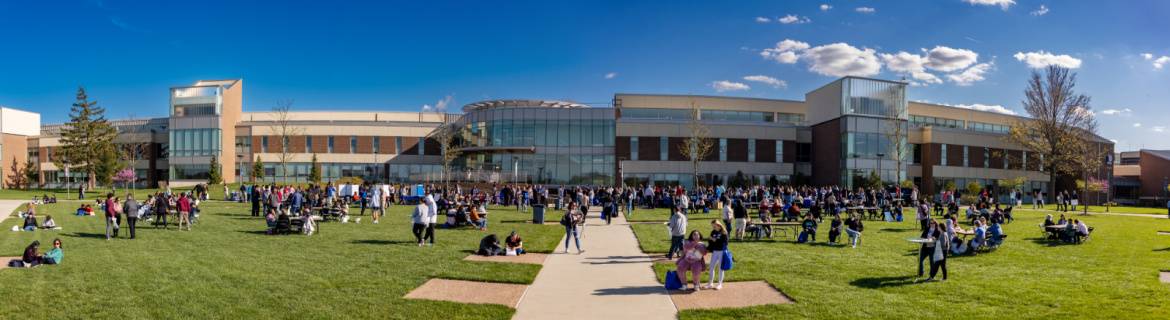 Harper campus exterior on a sunny day with people attending outdoor event